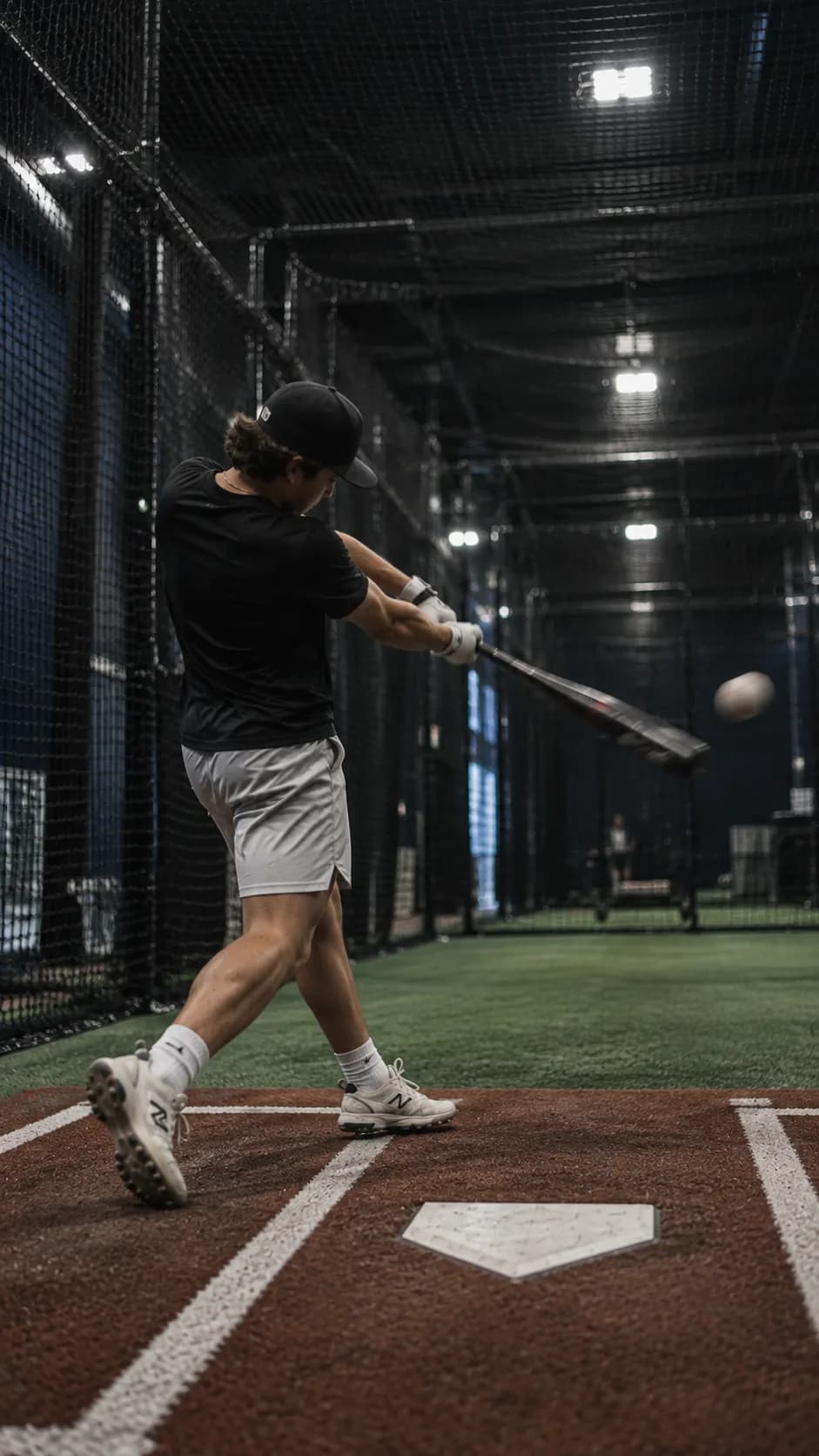 A hitter making contact inside a batting cage