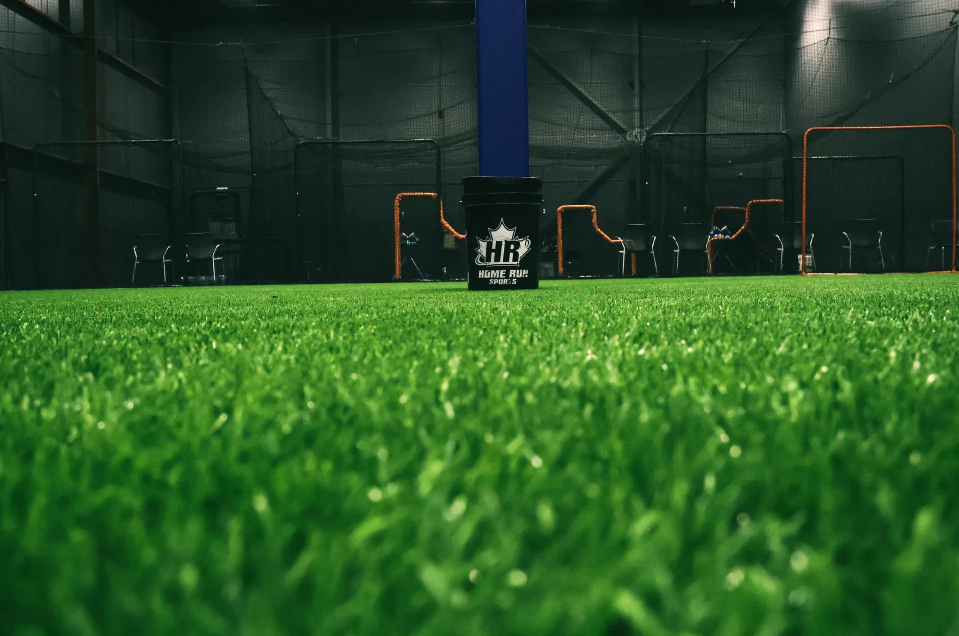 Ground-level view across the indoor turf toward the cages